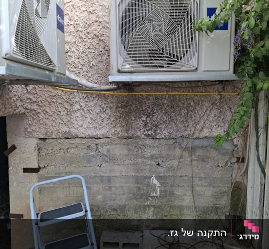 שני מזגנים מותקנים על קיר חיצוני עם סולם קטן.